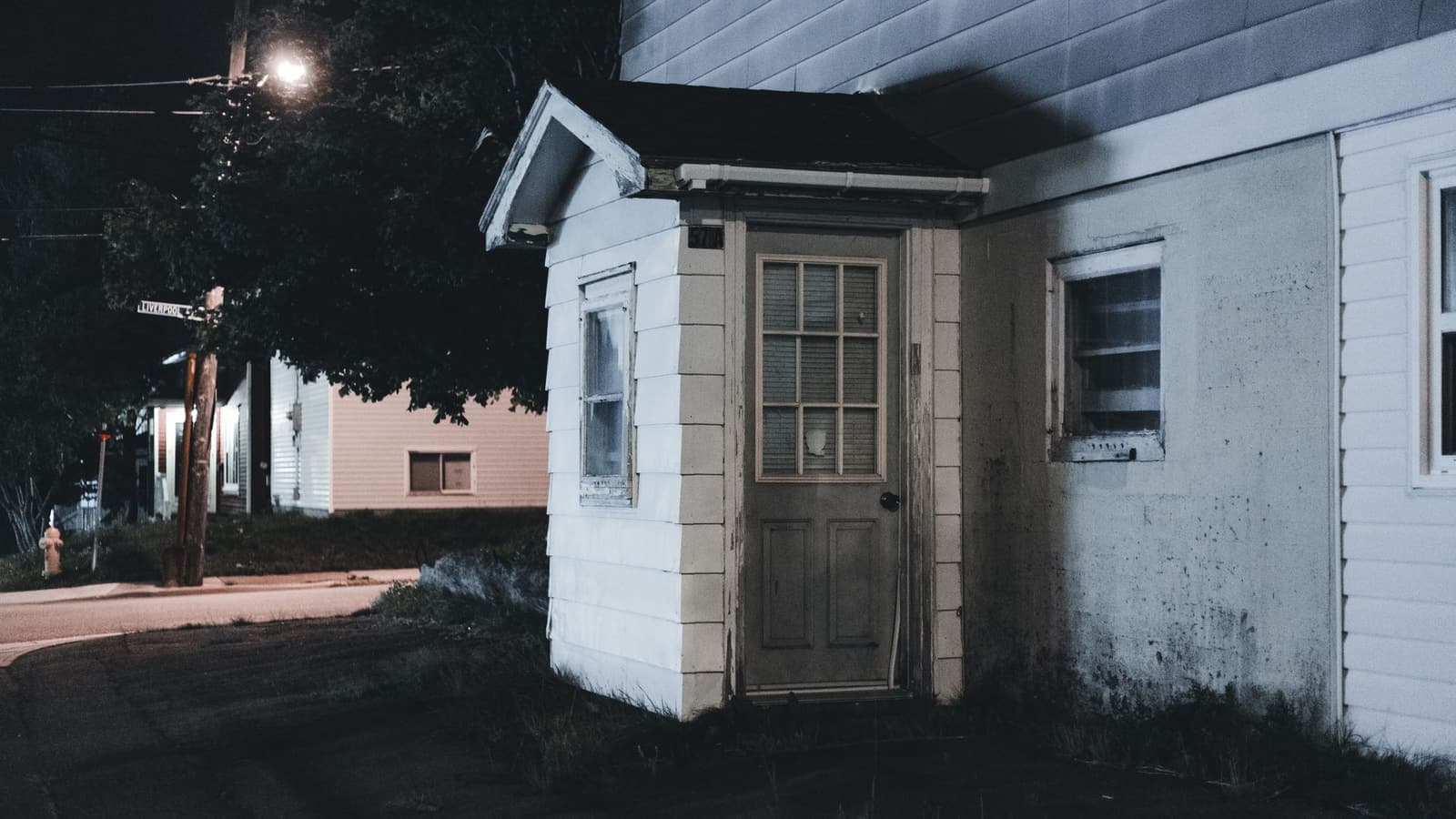 A house entrance with a wooden porch lit at night