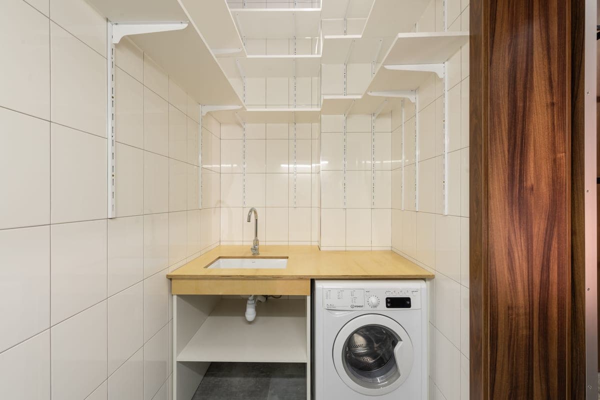 A minimalist laundry room with a washing machine and open shelving