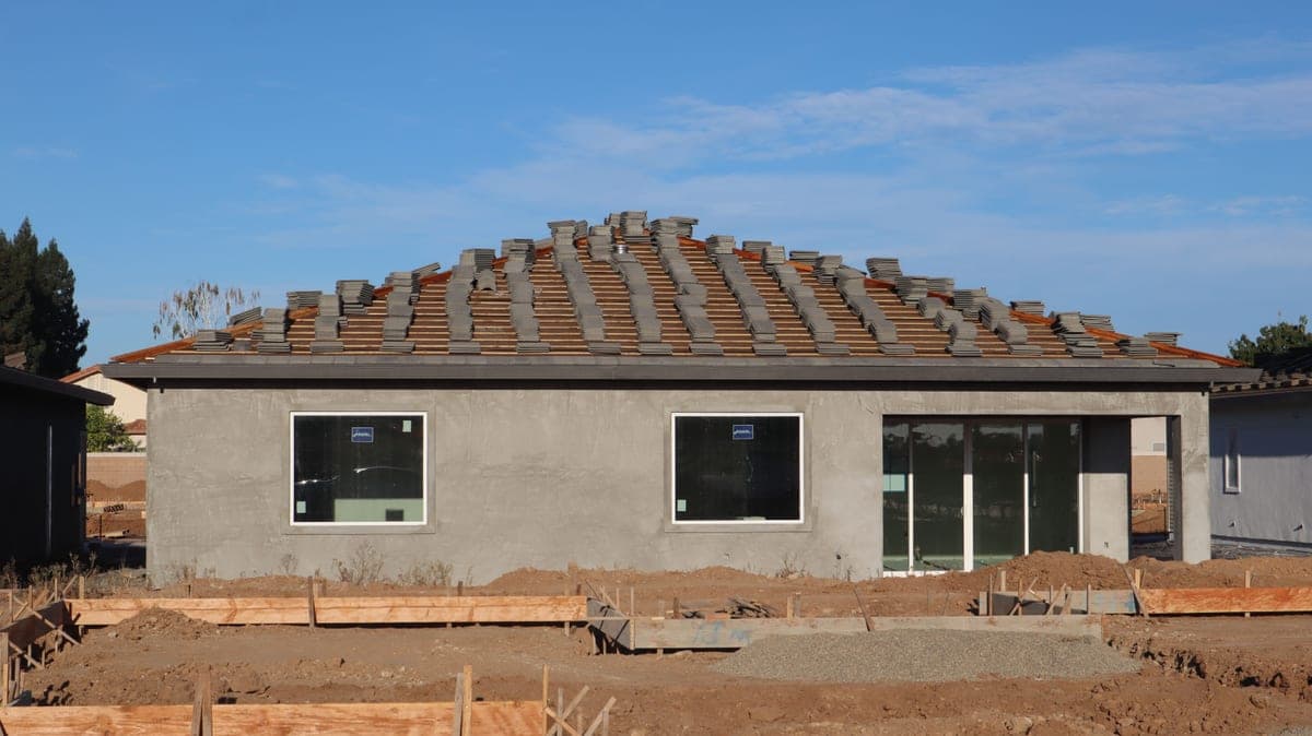 A new house under construction with a tiled roof and unfinished exterior