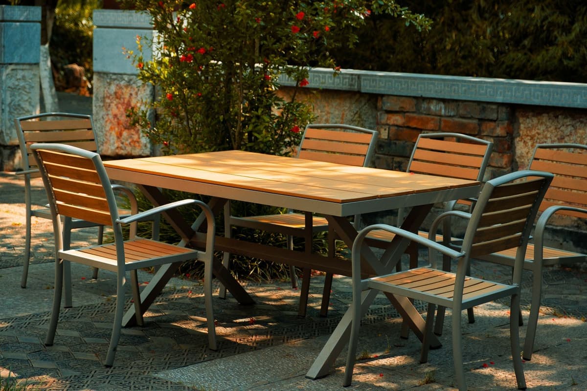 An outdoor patio with a wooden table and chairs in a garden setting