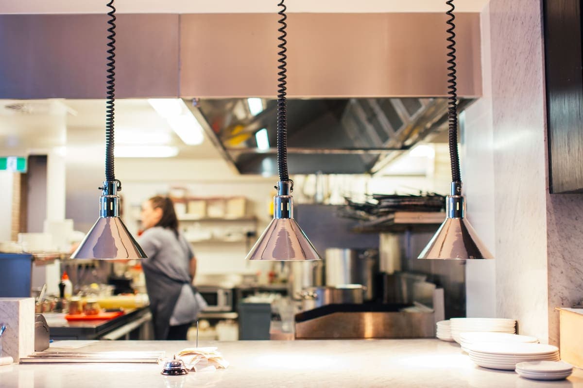A chef working behind a stainless steel restaurant kitchen counter