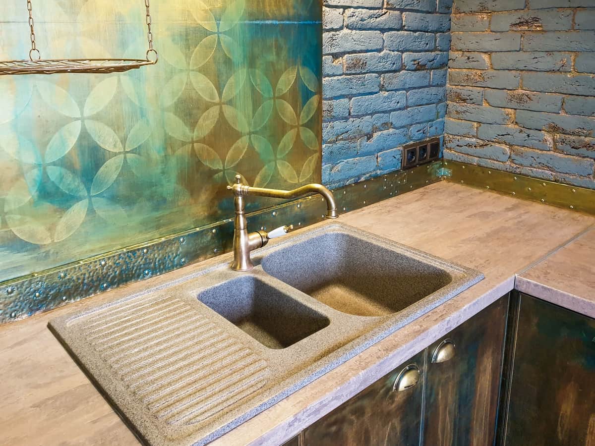 A rustic kitchen with a double sink and a brick wall