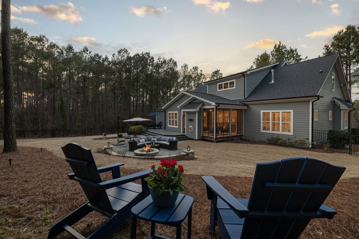 A backyard seating area with chairs and a fire pit at sunset