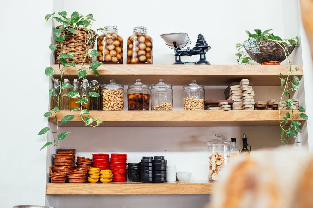 Timber shelves of glass jars beside potted plants
