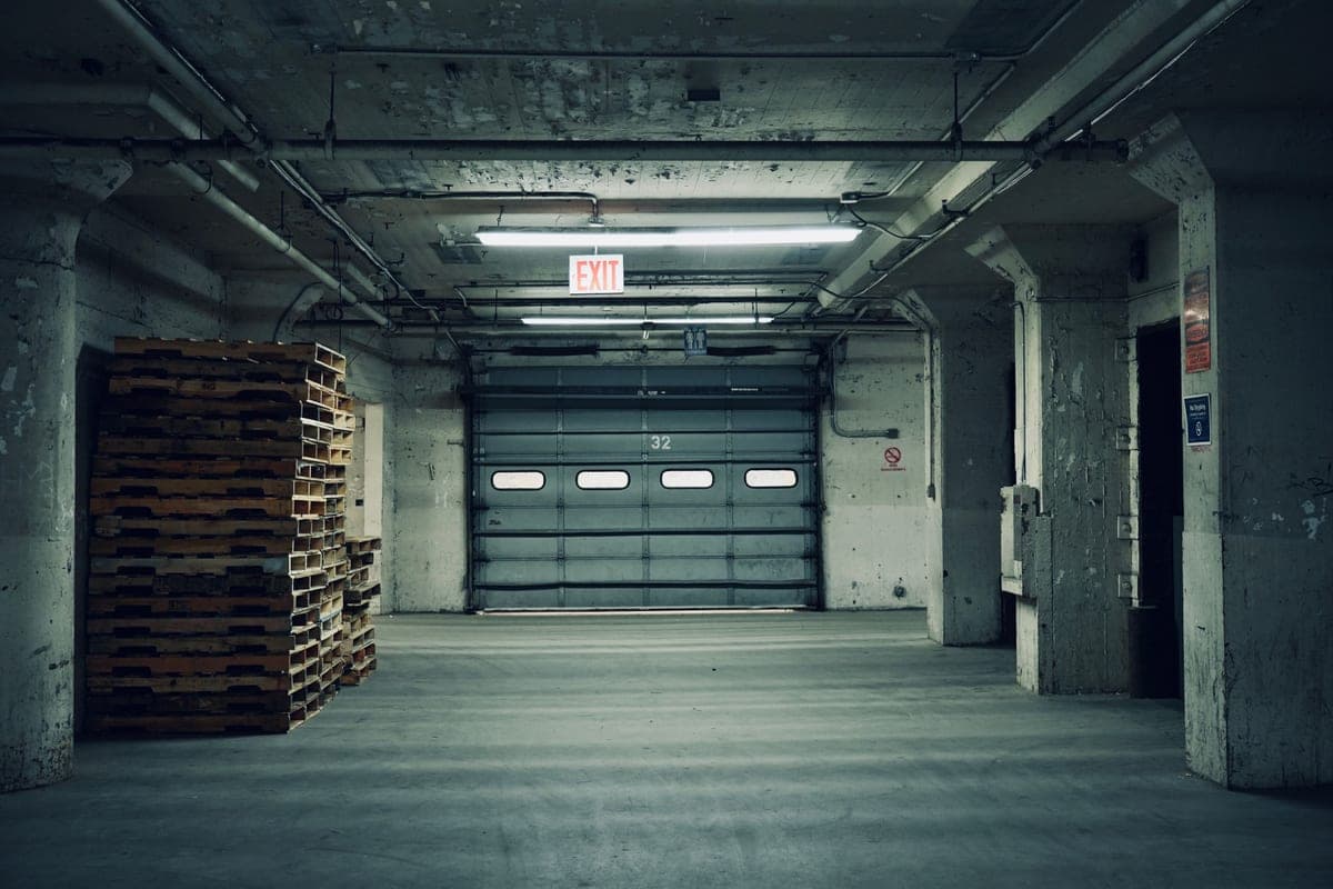 An empty industrial space with stacked pallets and a closed garage door