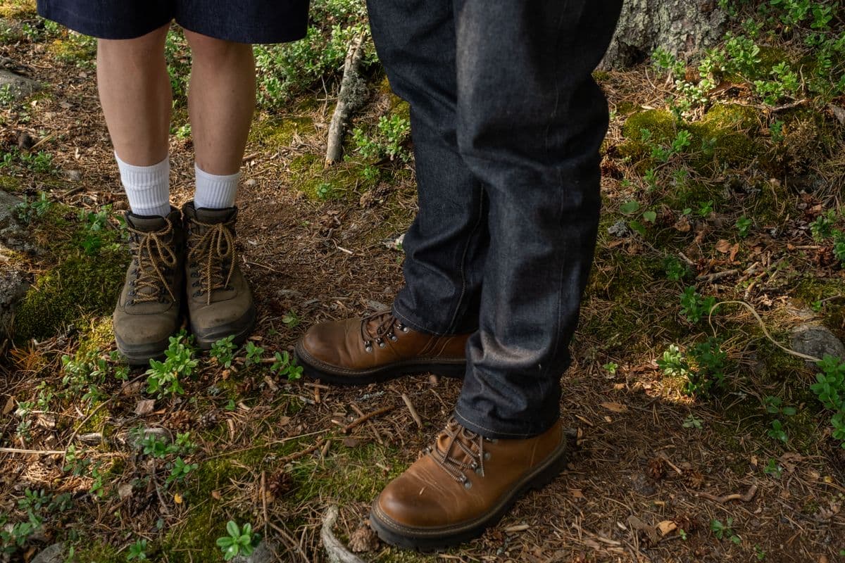Two people in hiking boots walking a forest trail