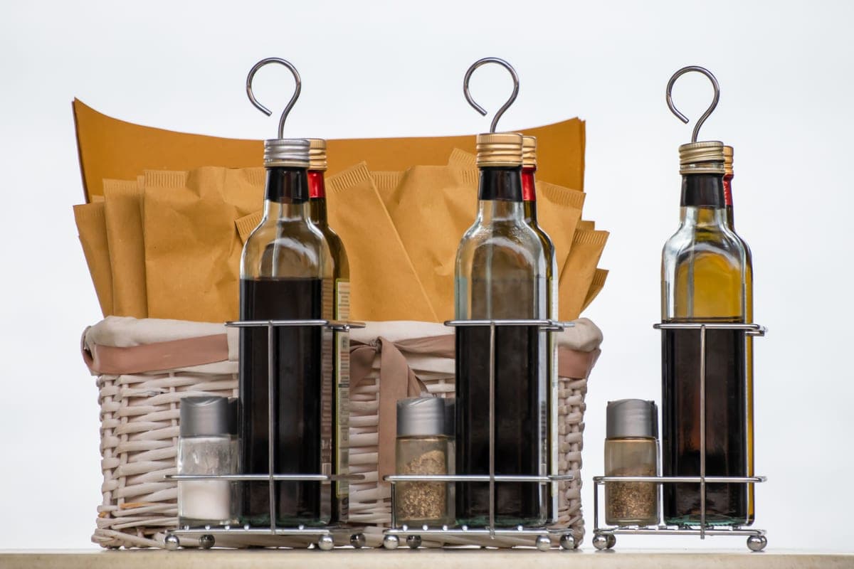 Glass bottles of condiments and spices in a wicker basket