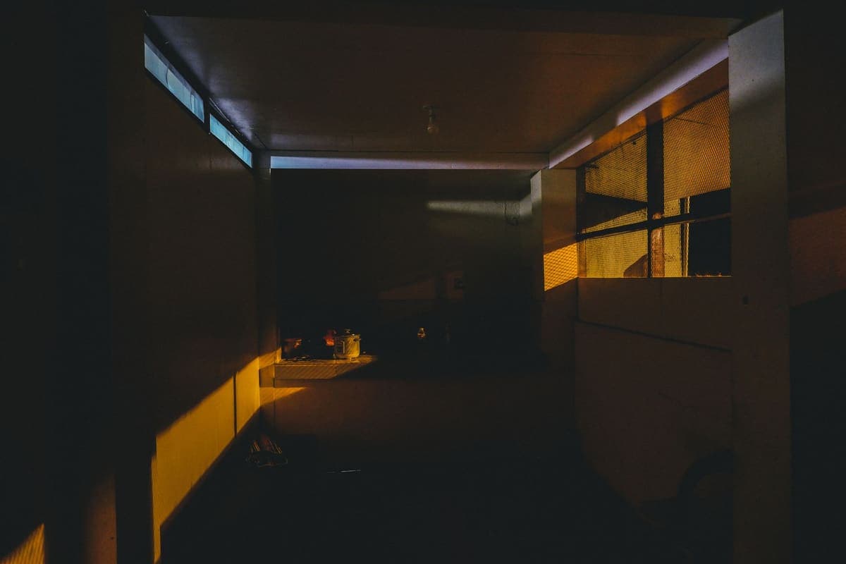 A dimly lit kitchen interior with dramatic lighting casting shadows