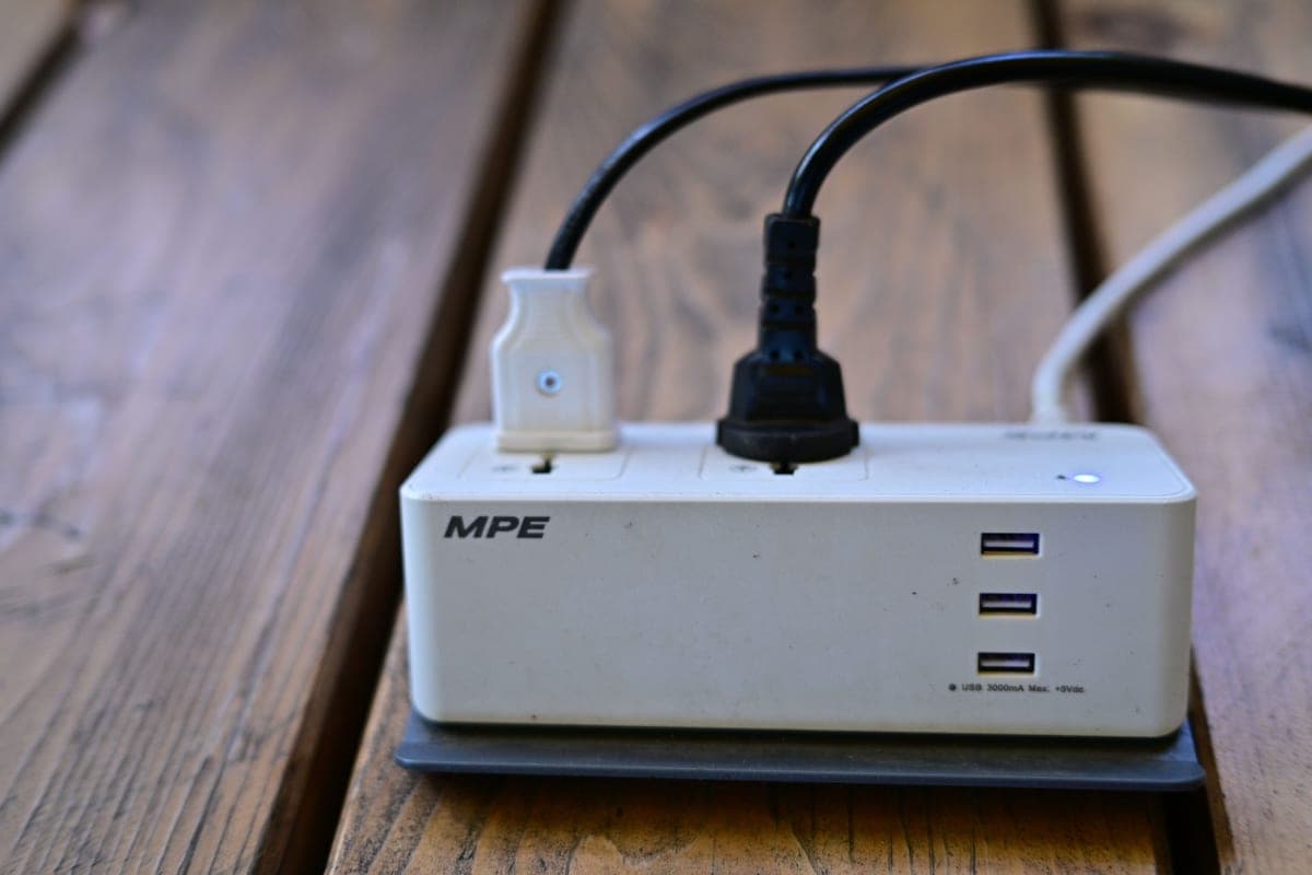 A power strip with several USB ports and cables on a wooden surface