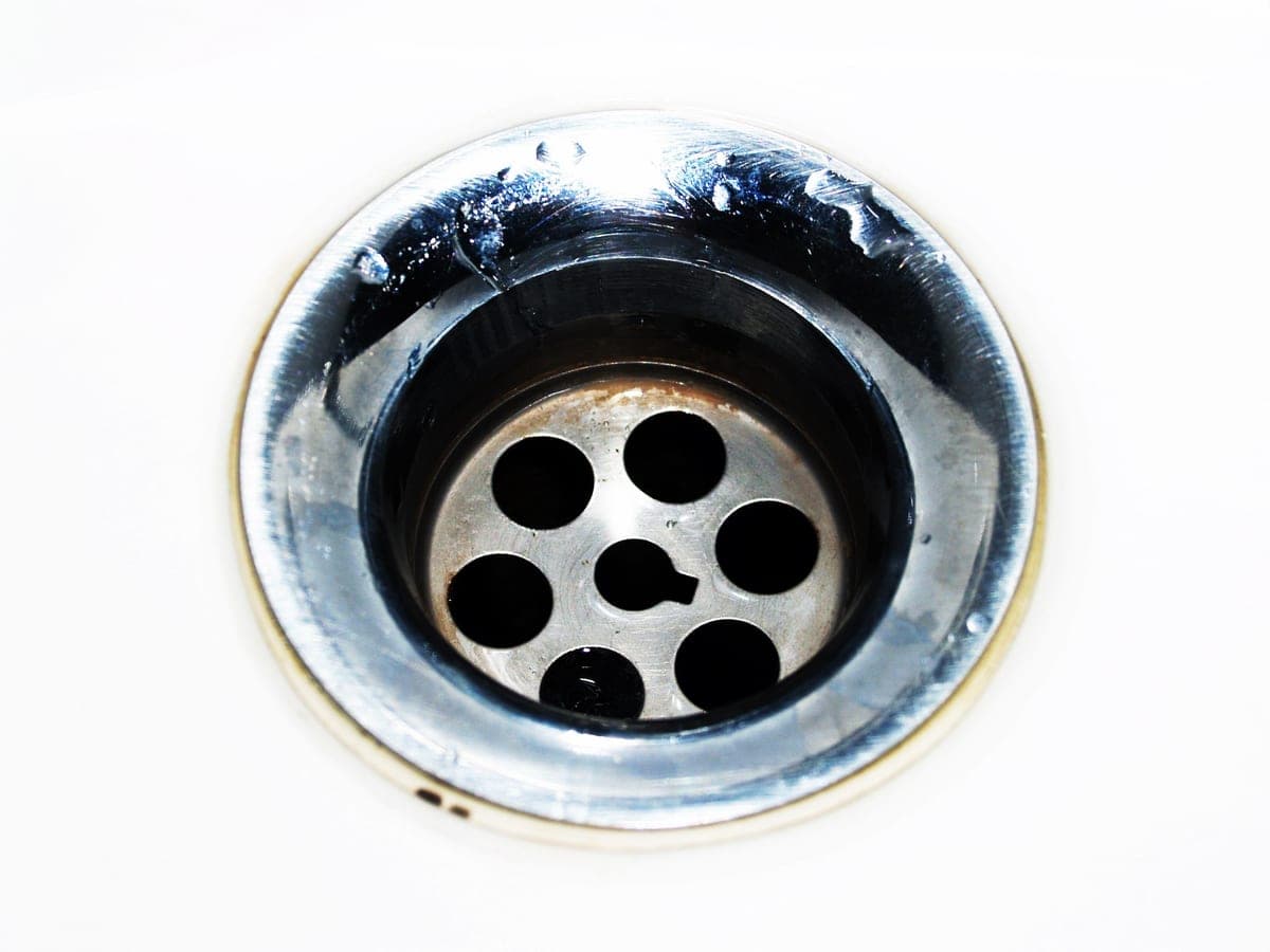 A chrome sink drain with water droplets
