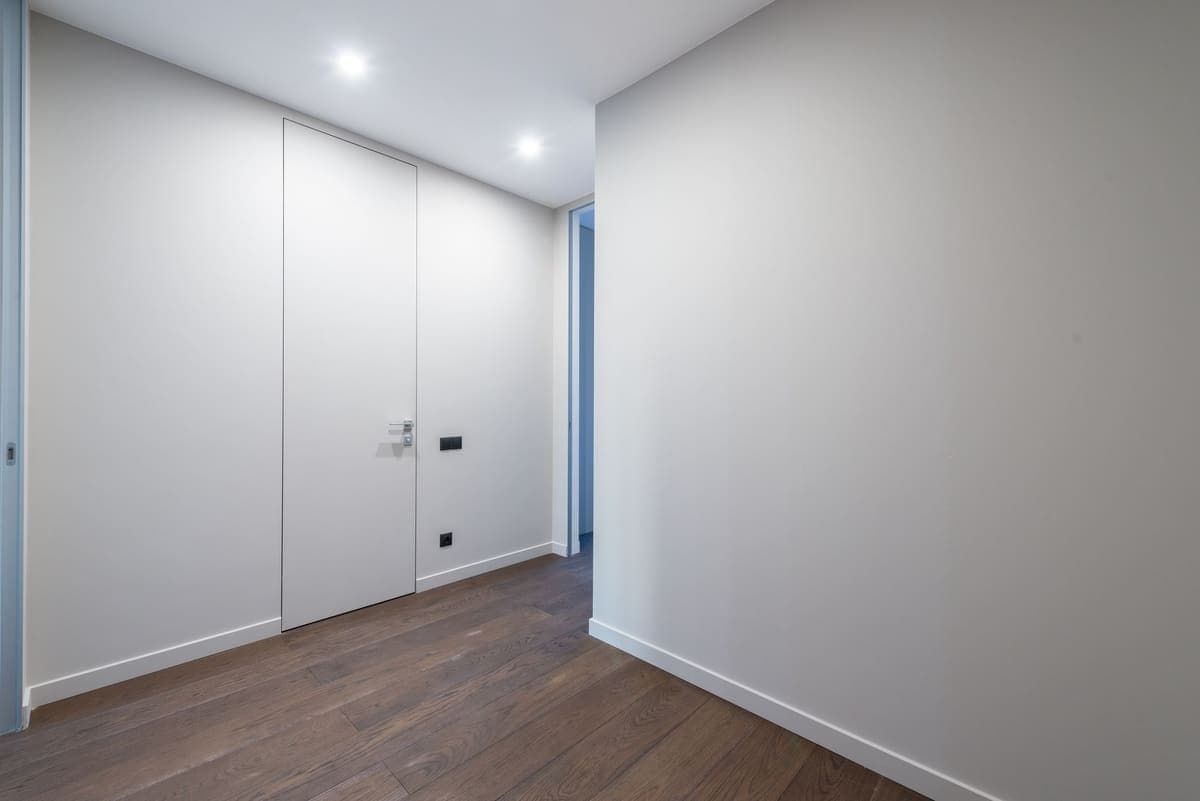A minimalist indoor corridor with sleek doors and wooden flooring