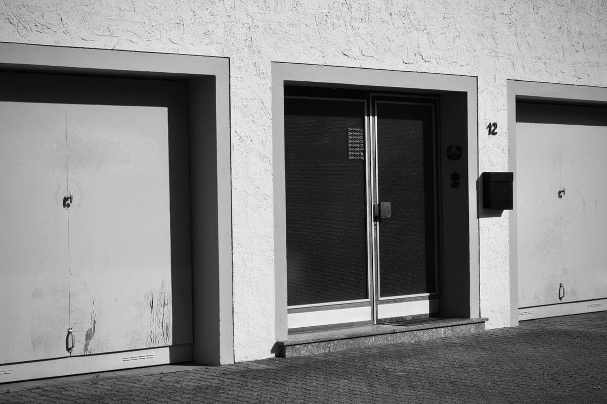 A monochrome photo of a building facade with garage doors