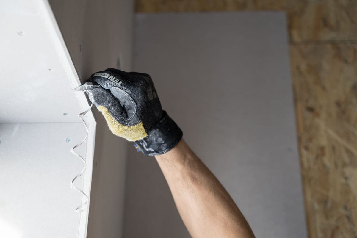 A gloved hand applying plaster to an interior wall