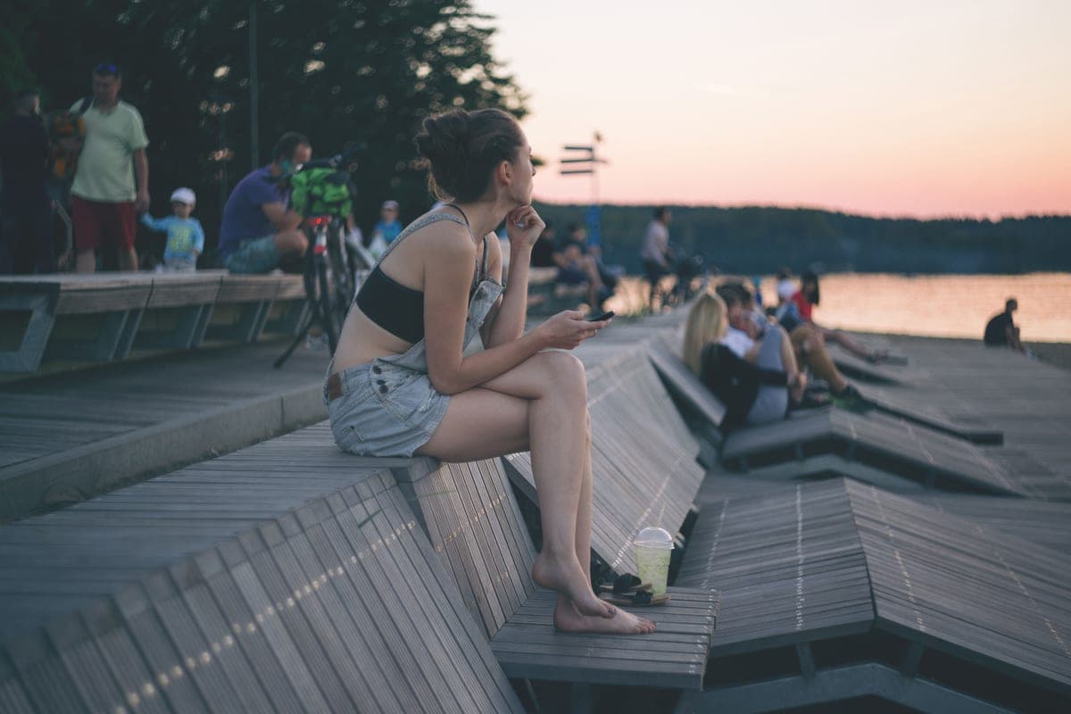A person sitting on a wooden deck by a lake at sunset