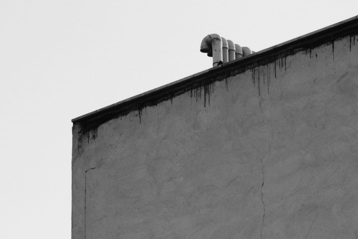 A concrete building edge with rooftop piping