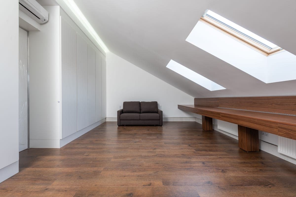 A spacious attic room with skylights and wooden flooring