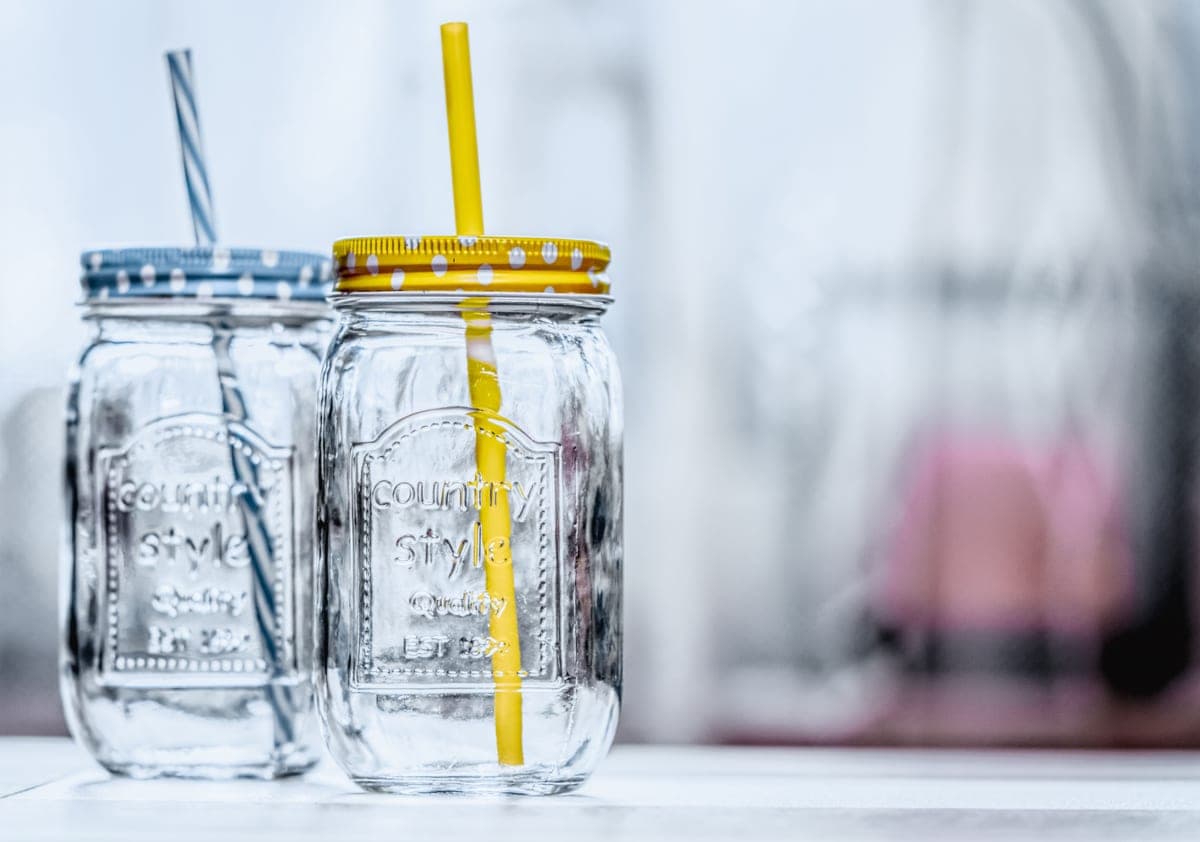 Two glass jars with polka-dot lids and straws