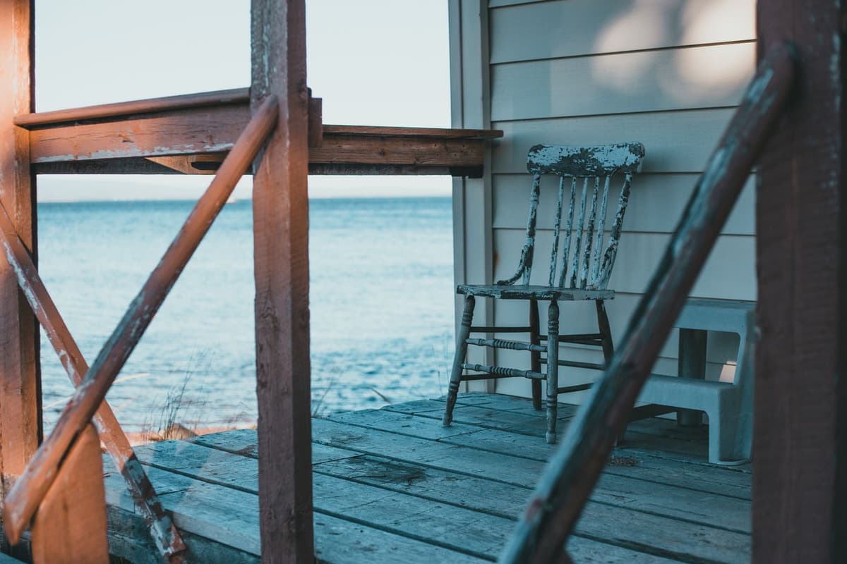 A wooden terrace with a chair looking out over the sea on a sunny day