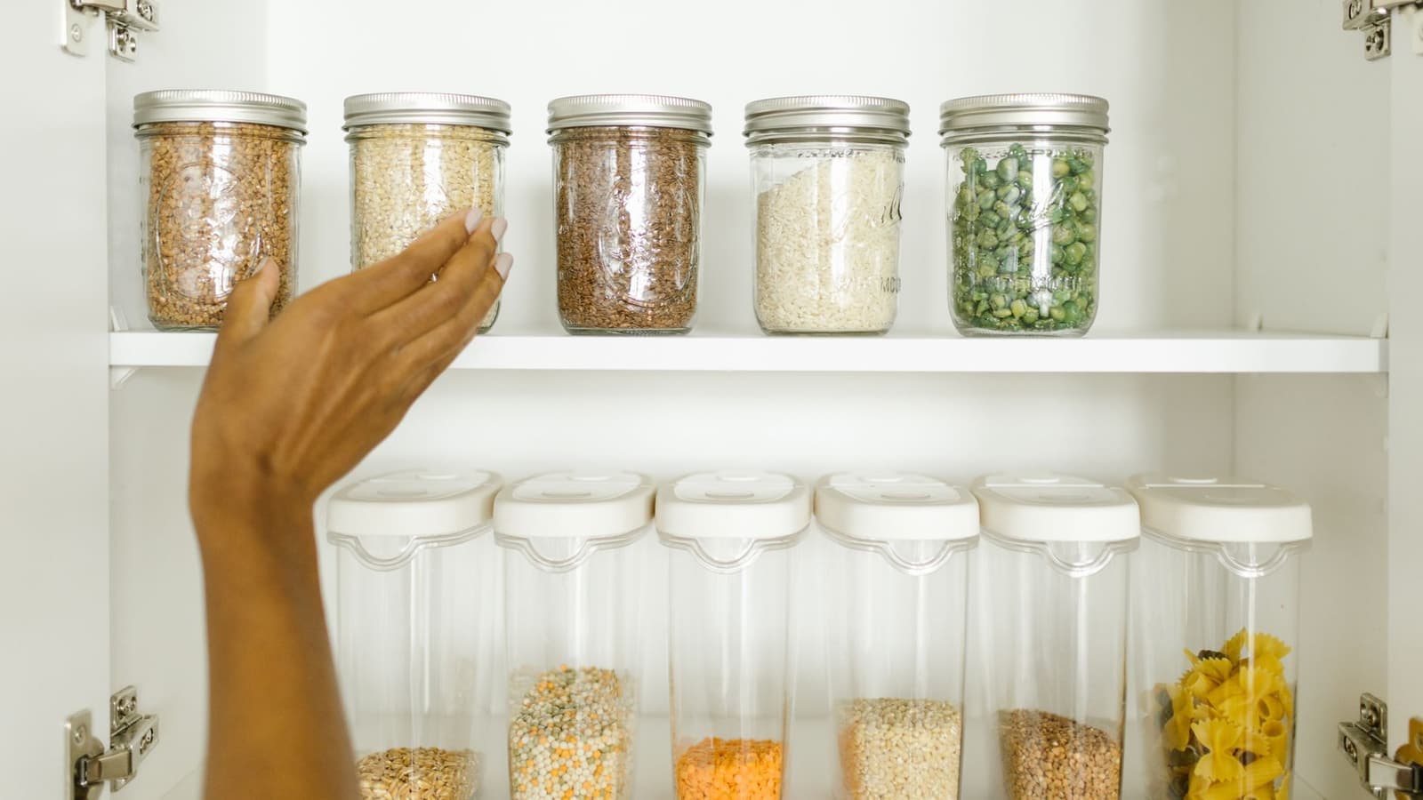 A tidy pantry shelf with grains stored in labeled glass containers