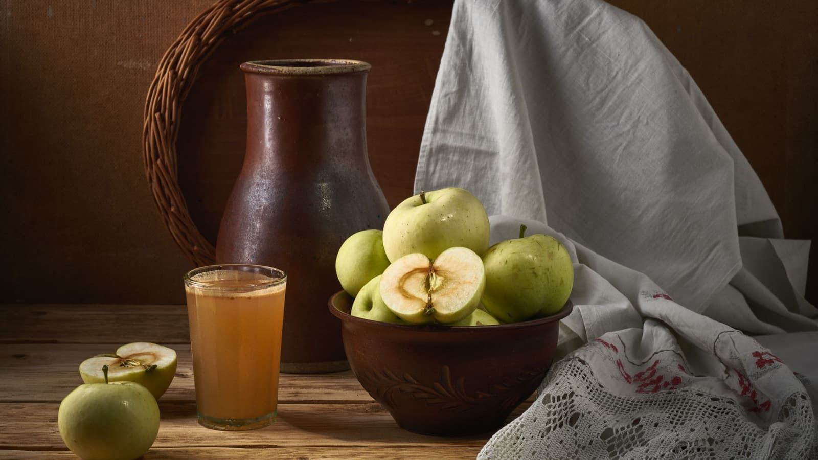 A rustic kitchen arrangement of apples, juice and earthenware jugs