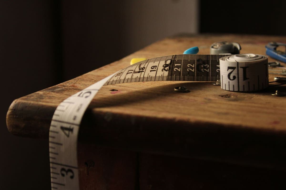 A rolled measuring tape on a vintage wooden table in warm light