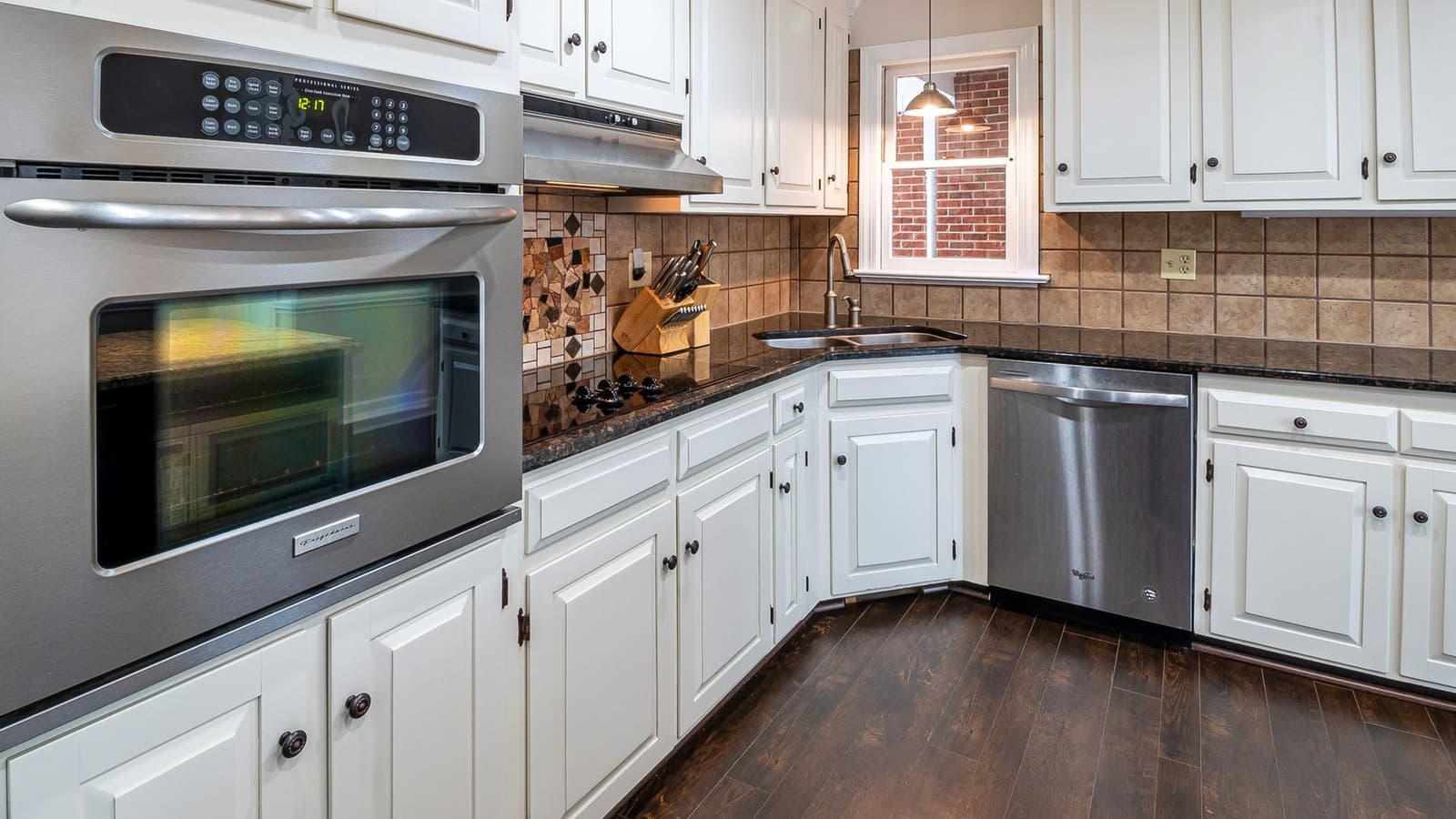 A bright kitchen with white cabinets and wooden flooring