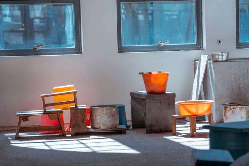 Plastic buckets and wooden stools in a rustic interior