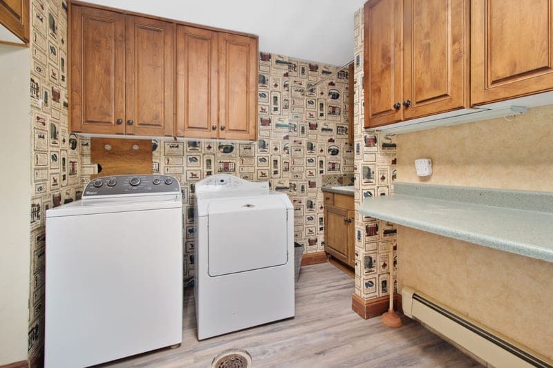 A laundry room with wooden cabinets, a washer and a dryer