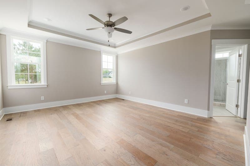 An empty room with wooden floors and a ceiling fan