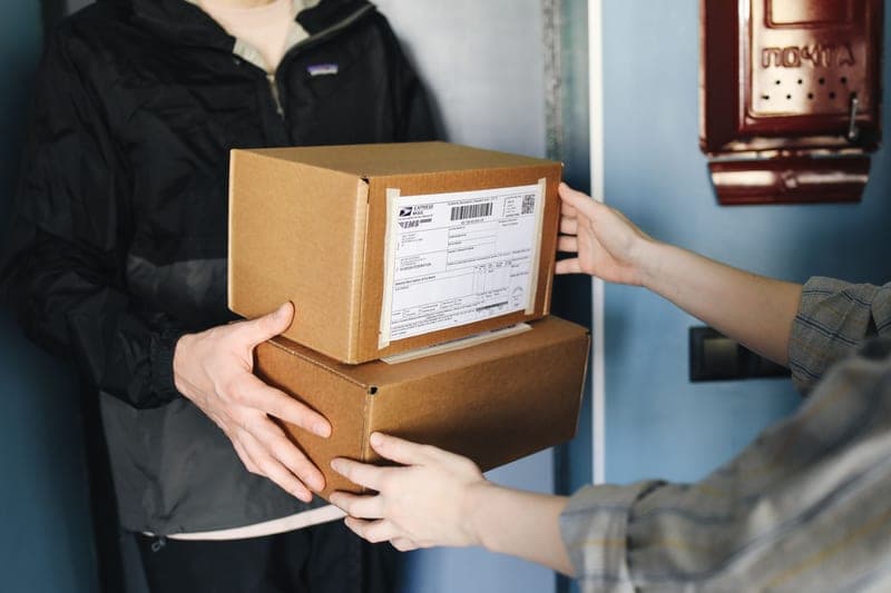 Hands passing a cardboard box indoors