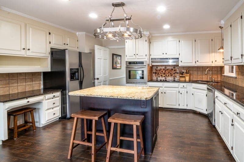 A kitchen with a granite island and hardwood floors