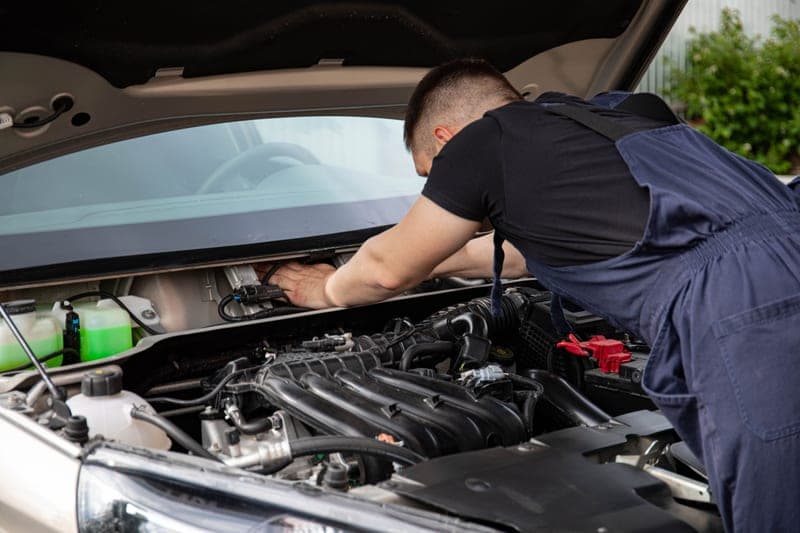 A mechanic working in the engine bay of a car