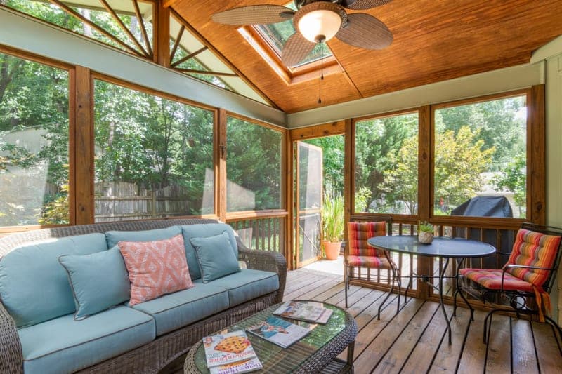 A screened porch with a wicker sofa under a skylight