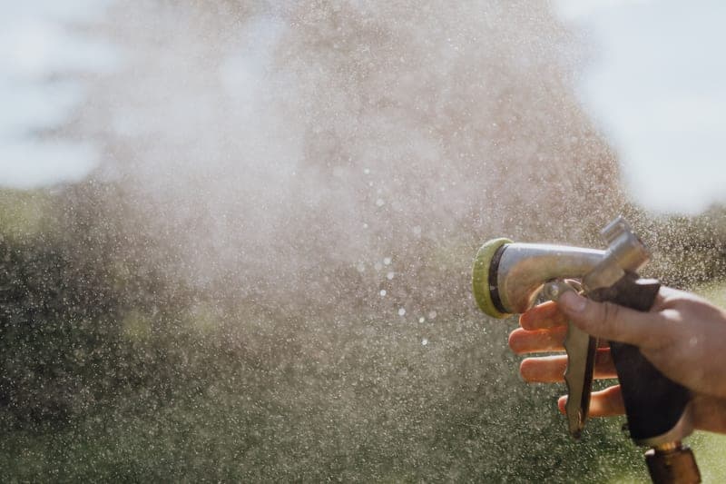 A hand misting water from a garden hose nozzle