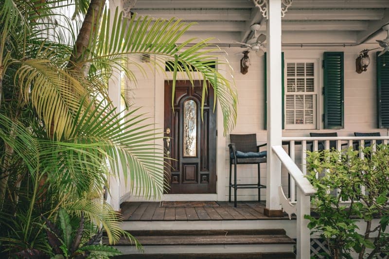 The front entrance of a house framed by tropical plants