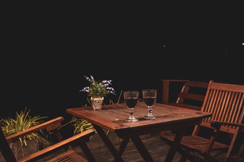 A wooden outdoor table set with glasses at night
